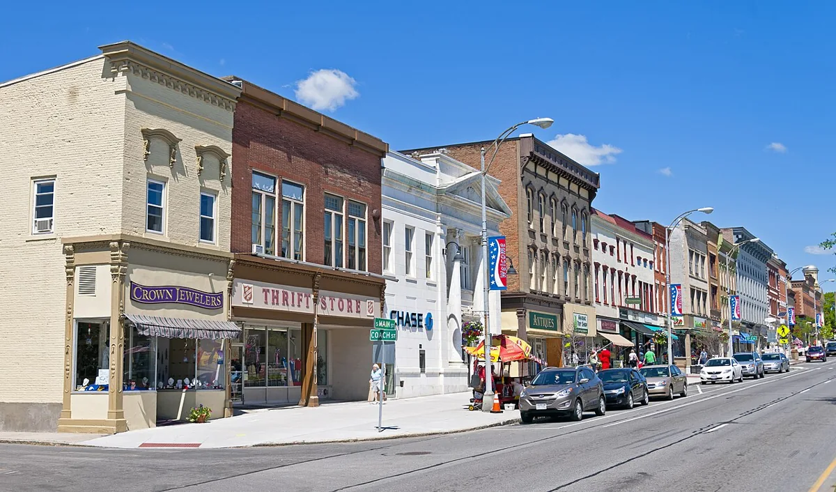 Historic storefronts, local shops, pedestrians, and parked cars along Main Street in Canandaigua.