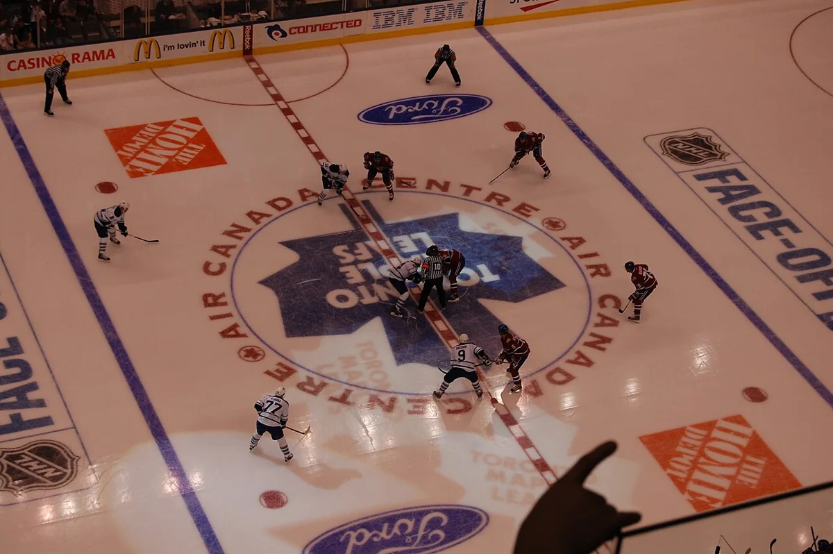 Montreal Canadiens and Toronto Maple Leafs players line up for a face-off at center ice.