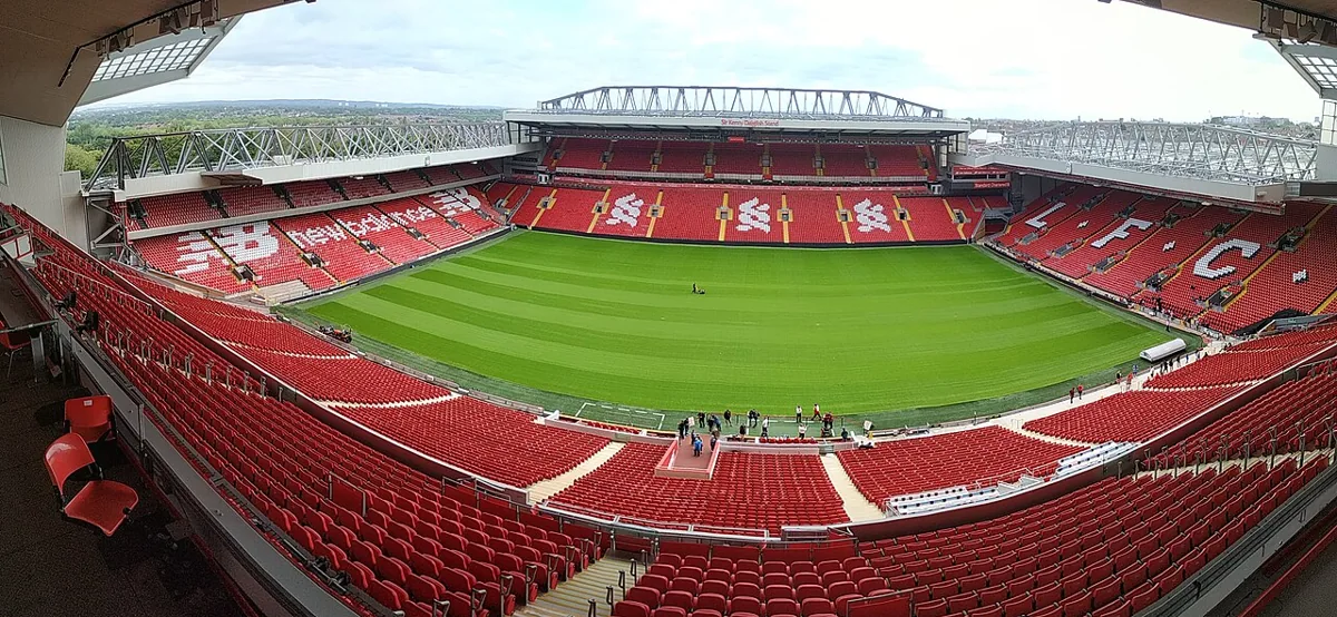 Anfield's green soccer pitch and red stands viewed from the main stand.